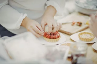 Préparation à plusieurs mains de tartelettes aux fraises.